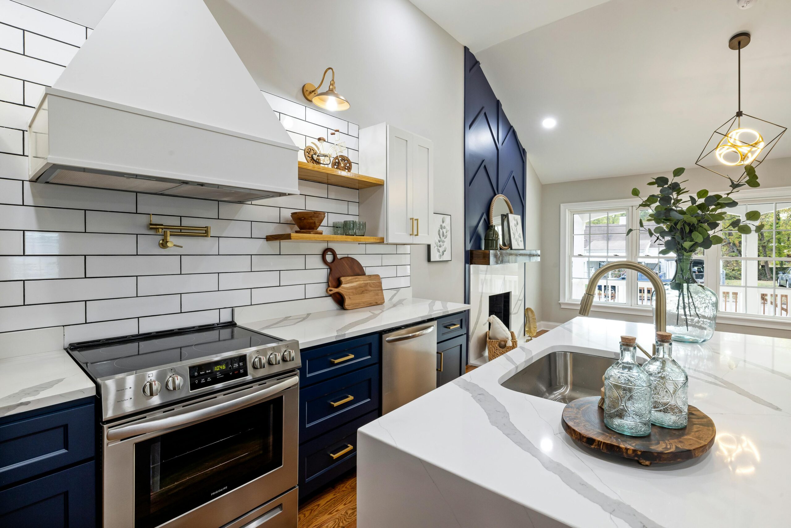 A modern kitchen featuring marble countertops, a stainless steel stove, and elegant blue cabinets.